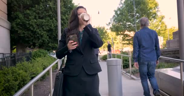 Бізнес-леді на мобільному телефоні, що йде по прогулянці з кавовою чашкою в 4k — стокове відео