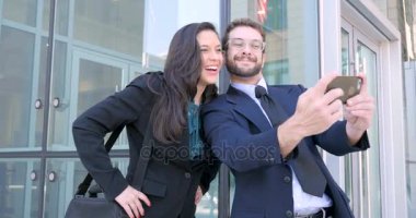 İyi giyimli erkek ve kadın selfie iş dışındaki akıllı telefon ile karmaşık almak