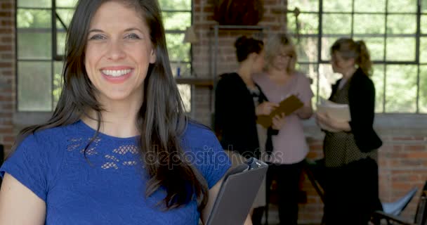 Zâmbind o femeie milenară la birou cu colegii care se uită la telefonul inteligent — Videoclip de stoc