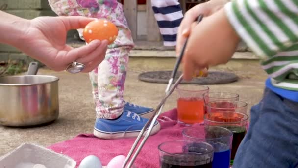 Niño y niña ayudan a su madre a colorear huevos de Pascua para las fiestas — Vídeos de Stock