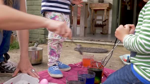 Mère et ses deux enfants teignant des œufs de Pâques ensemble à l'extérieur — Video