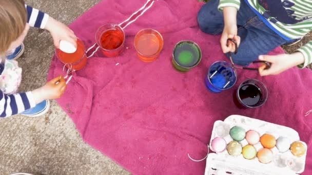 Overhead of young boy and girl coloring easter eggs and putting them in crate — Stock Video