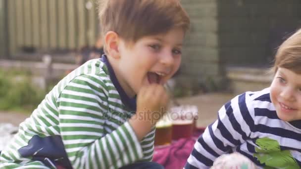 Een schattig gelukkig jong meisje en de jongen zitten buiten lachend samen — Stockvideo