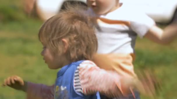 Dos niños pequeños saltando y jugando juntos afuera divirtiéndose — Vídeos de Stock