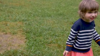 Mutlu gülümseyen genç yürümeye başlayan çocuk küçük kız dışarıda çimenlerde yürüyüş