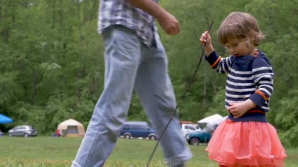 Bir baba genç yürümeye başlayan çocuk kızı bir park dışında giysileri ile yardımcı olur — Stok video