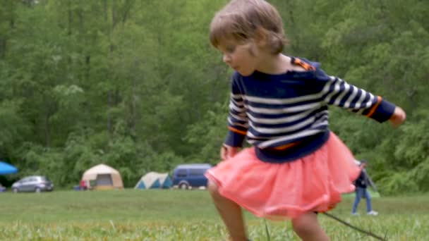 Klein meisje probeert te springen over een plas ontbreekt en krijgen bespat — Stockvideo