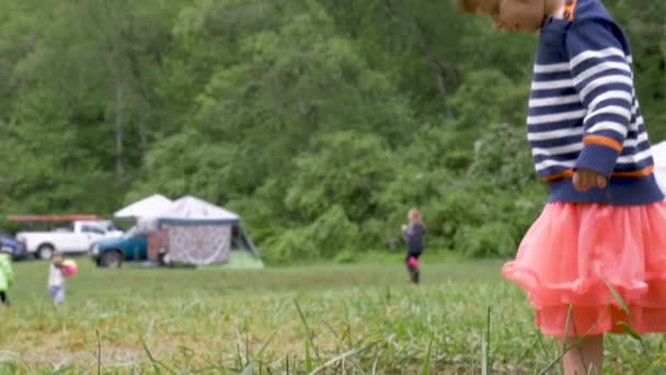 Adorable young girl looking down at the grass playing outside — Stock Video