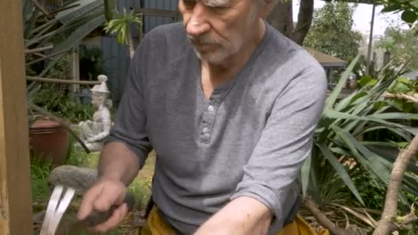 Aktiv pensionär senior man i 70-talet hamrar en spik som arbetar på ett hem projekt — Stockvideo