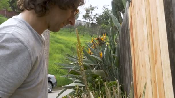 Ung man borra skruvarna i ett staket med en elektrisk borr — Stockvideo