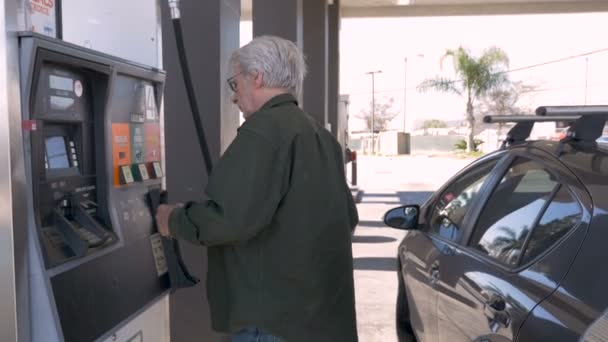 Homem idoso bombeando gasolina em seu carro a partir de um posto de gasolina self serve — Vídeo de Stock