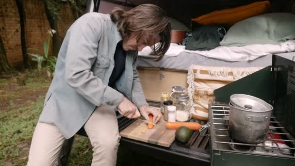Hipster young man cutting carrots while cooking and camping — Stock Video