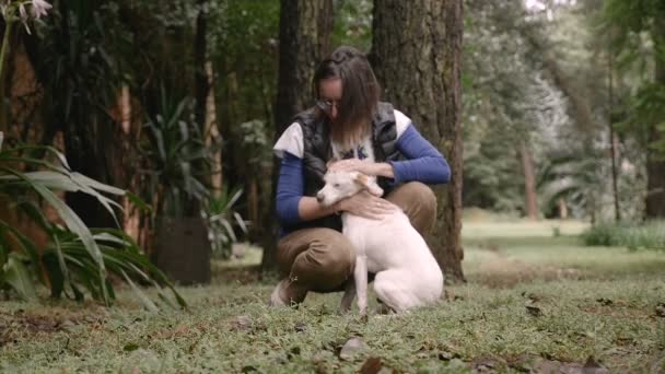 Portret van een gelukkige vrouw geknield op de grond haar hond aaien — Stockvideo