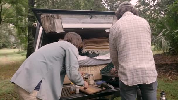 Dos hombres empacando su equipo de campamento en la parte trasera de su camioneta — Vídeo de stock