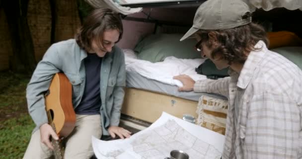 Push in de deux hommes regardant une carte ensemble tout en voyageant dans un petit camping-car — Video