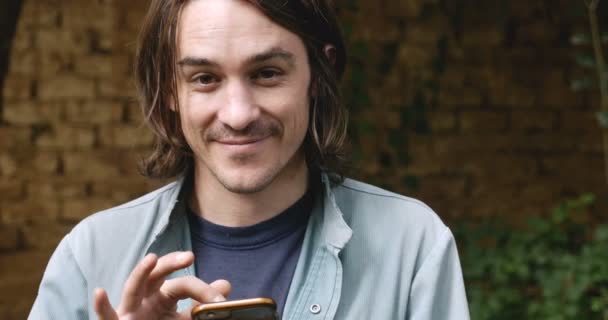 Retrato de un atractivo hombre de 20 o 30 años usando un teléfono inteligente - dolly — Vídeos de Stock