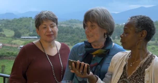 Drei quirlige Seniorinnen um die 60 machen im Urlaub Selfies mit dem Smartphone — Stockvideo
