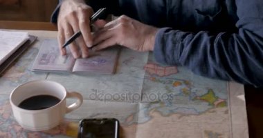 Not defterinde yazarken onun pasaport pulları ve bir dünya haritası bakarak adam