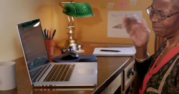 Зрелая черная женщина страдает от боли в шее во время работы над ноутбуком — стоковое видео