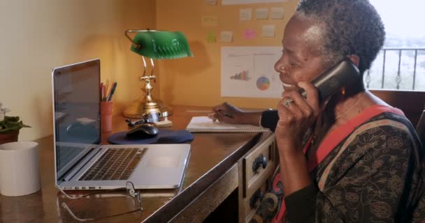 Mujer negra madura feliz colgando su teléfono inalámbrico en la oficina en casa — Vídeo de stock