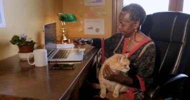 Afrikalı-Amerikalı kadın onun kucağına bir kedi ile evden çalışma