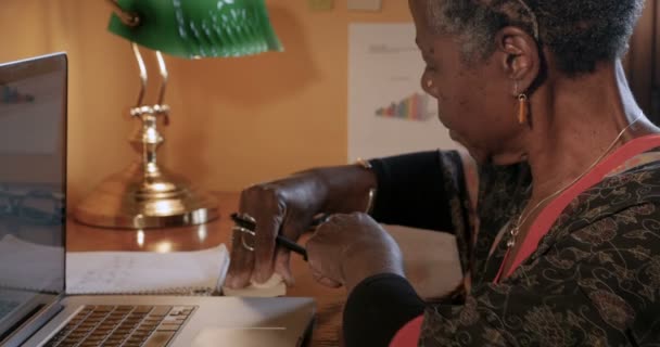 Ώριμη γυναίκα επαγγελματίας μαύρο γράφοντας υπενθυμίσεις σε κολλώδεις σημειώσεις στο γραφείο της — Αρχείο Βίντεο