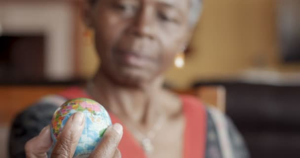 Afrikanerin hält eine kleine Weltkugel in der Hand und betrachtet sie