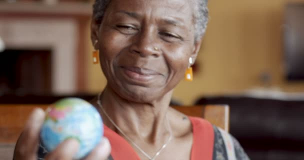 Glücklich lächelnd afrikanisch-amerikanische reife Frau über 50, die eine Weltkugel betrachtet — Stockvideo