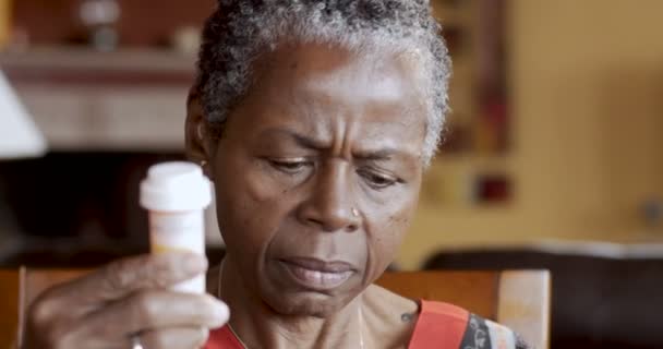 Afro-americano sênior mulher colocando em óculos para ler seu frasco de prescrição — Vídeo de Stock