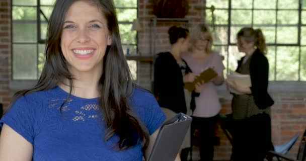 Lächelnde Millennial-Frau im Büro mit Kollegen, die aufs Smartphone schauen — Stockvideo