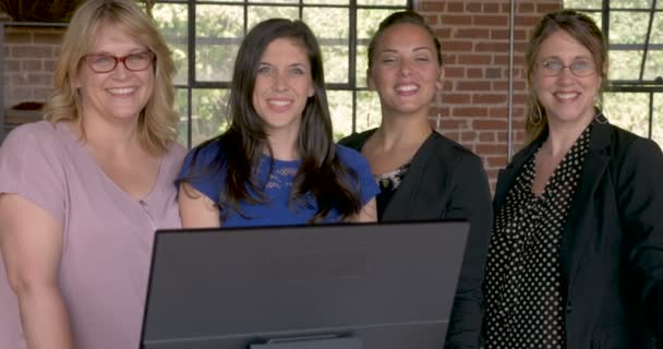Four professional women smiling behind a computer in modern startup office — Stock Video
