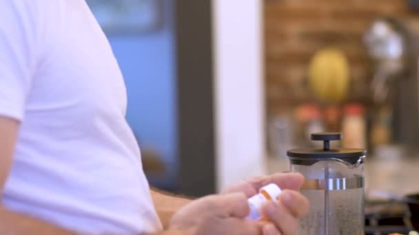 Hombre tomando pastillas de medicamentos de un frasco de medicamentos recetados en la cocina — Vídeos de Stock