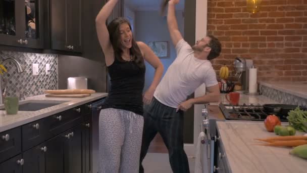 Успішний щасливий чоловік і жінка танцюють разом на своїй сучасній кухні — стокове відео