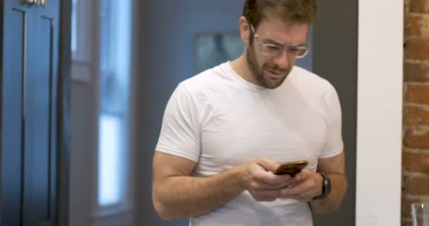 Jonge man met behulp van mobiele telefoon pompen arm in de lucht viert succes dansen — Stockvideo