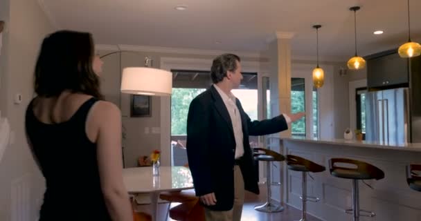 Makler zeigt einem aufgeregten jungen Paar ein modernes Zuhause — Stockvideo