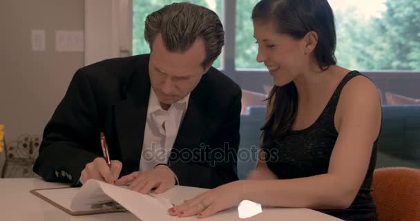 Attraktiver Mann und schöne Frau unterschreiben gemeinsam Papiere in einem Haus — Stockvideo