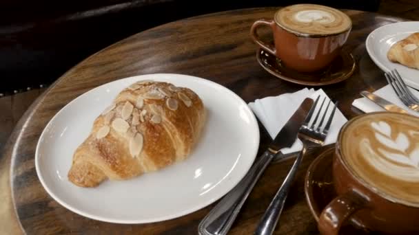 Alacsony szög a latte art és mandula croissant a sötét fából készült asztal