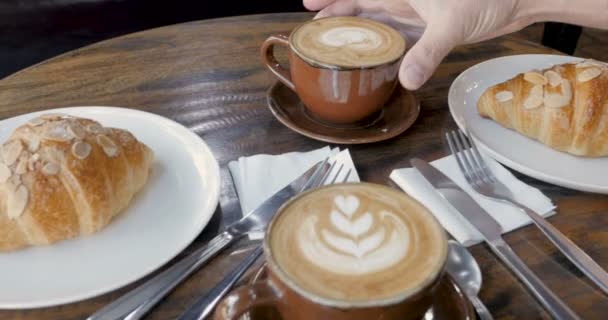 Рука протягивает руку, чтобы взять чашку кофе, берет напиток и кладет его обратно — стоковое видео