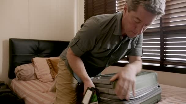 Mannen kämpar att zippa upp hans bagage medan packning för en resa i slow motion — Stockvideo