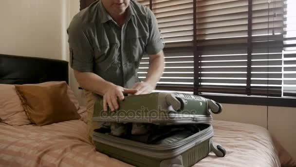 El hombre tiene dificultades para empacar su maleta rellena en cámara lenta — Vídeos de Stock