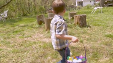 Genç çocuk bir bahçede yürürken yumurta Paskalya bulmaya konsantre