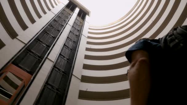 Turystyczna człowiek sobie plecak patrząc na niebo przez okrągły budynek — Wideo stockowe
