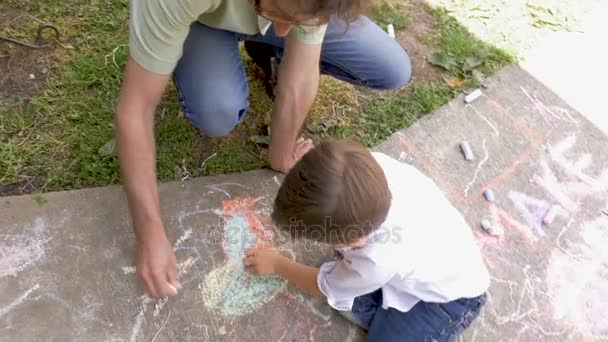 Overhead shot of a man and young boy coloring with chalk outside — Stock Video