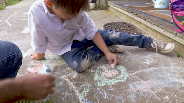 4-5 jähriger Junge zeichnet mit Kreide mit seinem Vater mit der linken Hand — Stockvideo