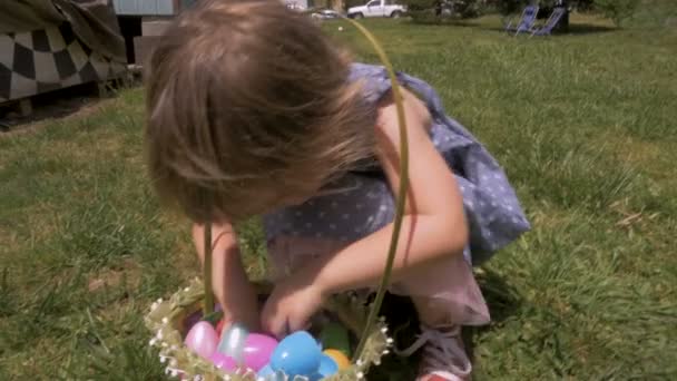 Чарівна маленька дівчинка відкриває шматочок цукерок зі свого великоднього кошика — стокове відео
