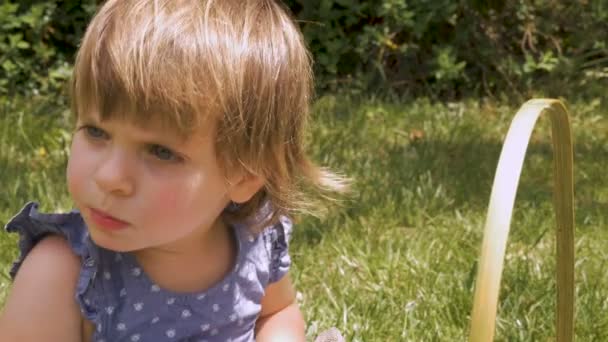 Nahaufnahme eines schönen kleinen Mädchens, das kaut und in die Ferne schaut — Stockvideo