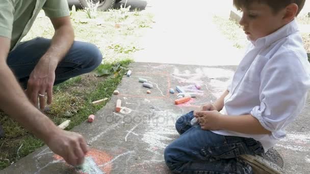 Padre e figlio disegnano insieme con gesso su un marciapiede — Video Stock