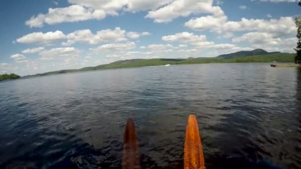 POV de dois esquis aquáticos de madeira vintage flutuando em um lago enquanto um barco passa — Vídeo de Stock