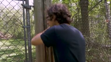 İzinsiz girmek ve bir zincir bağlantı çit ile kırma bir insanın ağır çekim