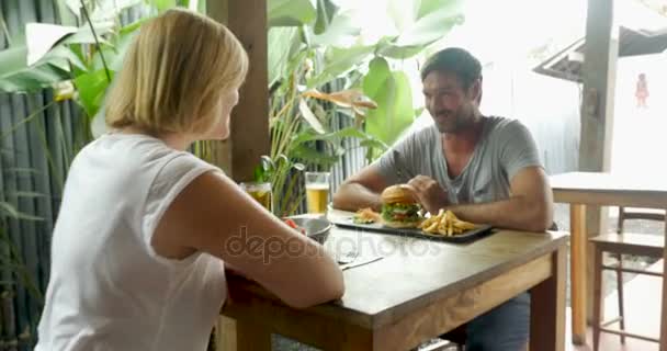 Homem bonito e mulher atraente torcer com um copo de cerveja em um restaurante — Vídeo de Stock